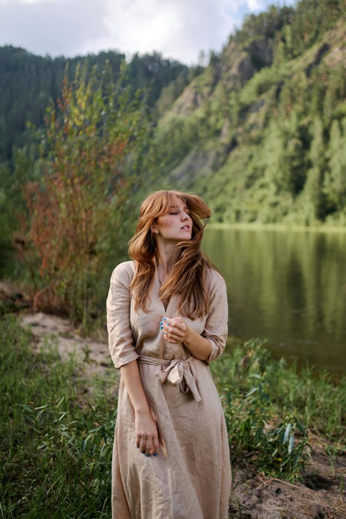 Dreamy woman with flying hair against mount and pond